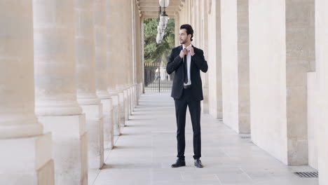 businessman adjusting tie in a parisian corridor