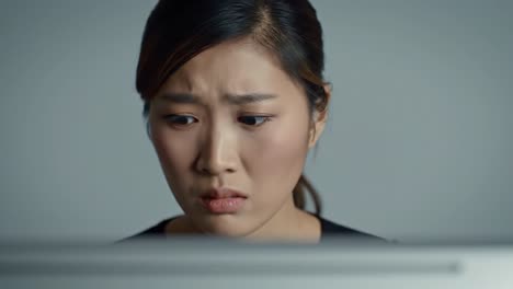 a woman displays a shocked expression as she sits at her desk, looking intently at her computer screen. her brows are furrowed and mouth slightly open, indicating surprise or concern.