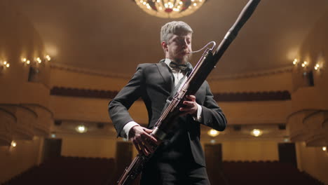 talented bassoonist with bassoon on scene of old opera house or music hall portrait of musician