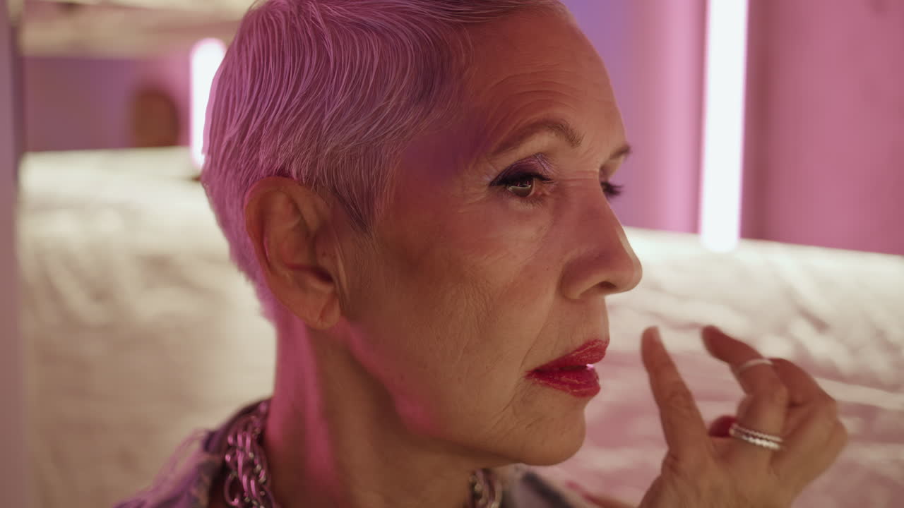 Stylish lady looking mirror reflection closeup. Trendy senior touching makeup