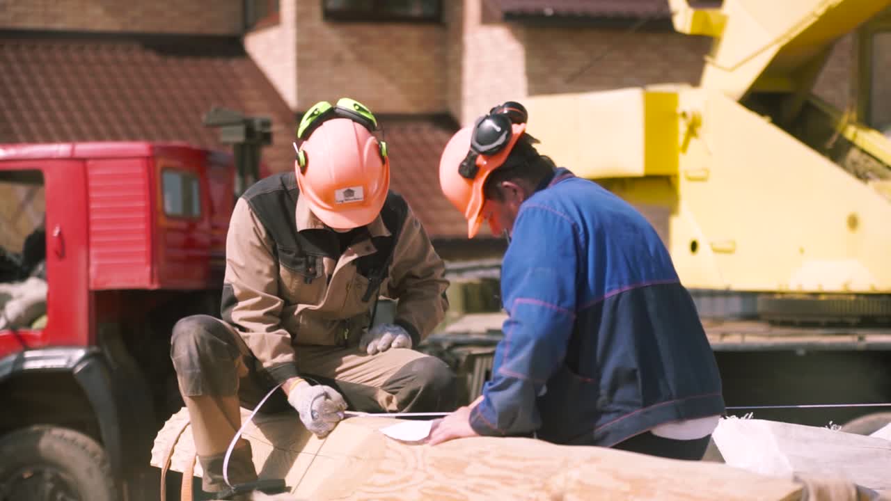 trabajadores de la construcción que miden madera en el sitio de construcción