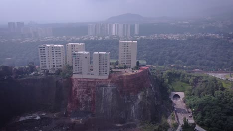 Grupo-De-Cinco-Edificios-De-Apartamentos-Blancos-Construidos-En-Un-Acantilado-Visto-Con-Un-Dron-Al-Lado-Del-Parque-La-Mexicana-En-La-Parte-Occidental-Del-Distrito-De-Cuajimalpa-En-La-Ciudad-De-México,-En-Un-Día-Con-Poca-Niebla