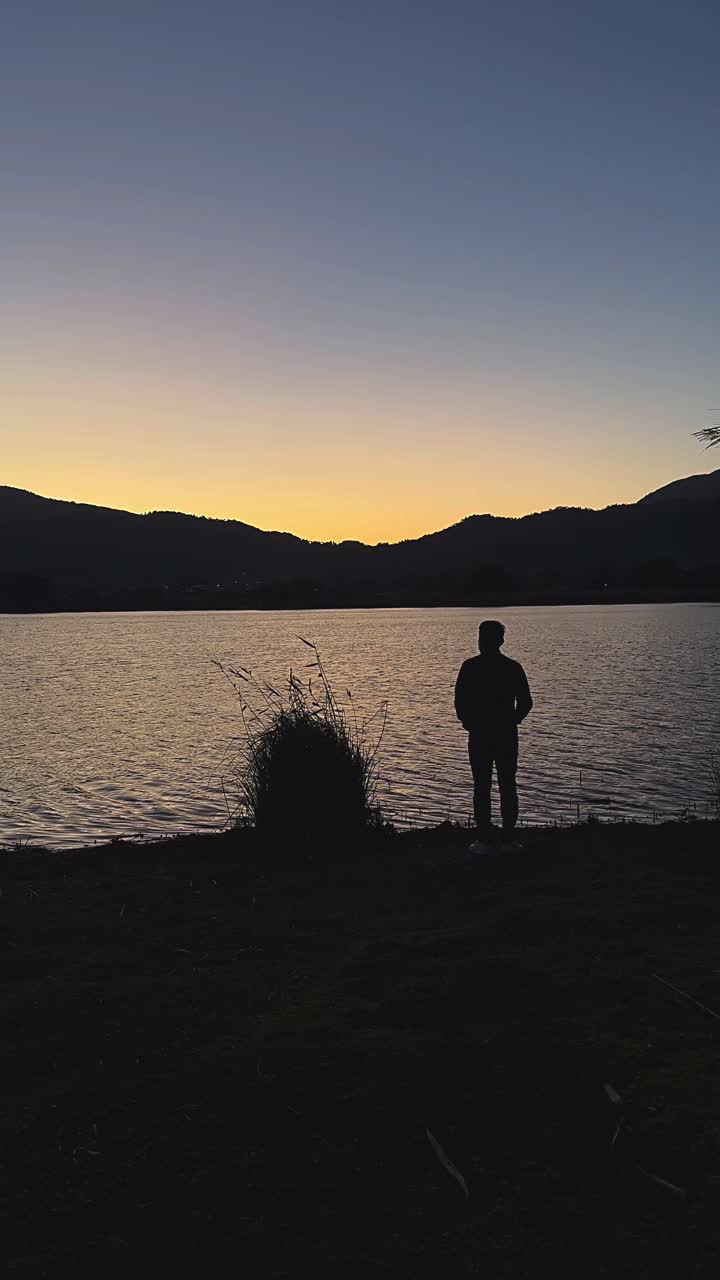 hombre viendo la puesta de sol sobre el lago