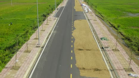 Vista-De-Drones-Del-Agricultor-Está-Secando-Arroz-En-Una-Carretera-En-La-Provincia-De-Khanh-Hoa,-Vietnam-Central