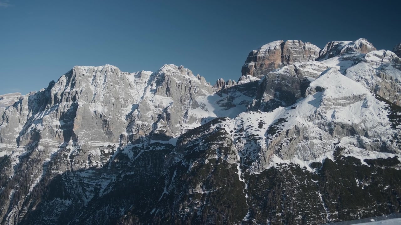 Cime montuose innevate e cresta rocciosa, ripresa statica a mano libera. Vista panoramica dall'alto di una maestosa catena di cime alpine con neve bianca, ghiaccio e pietra fredda.