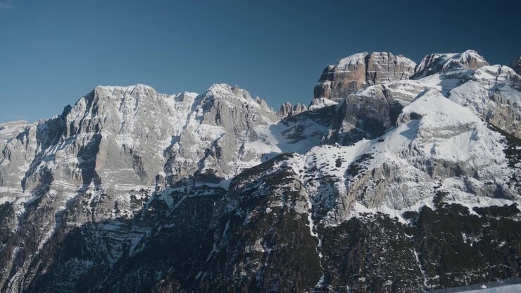 Cime montuose innevate e cresta rocciosa, ripresa statica a mano libera. Vista panoramica dall'alto di una maestosa catena di cime alpine con neve bianca, ghiaccio e pietra fredda.