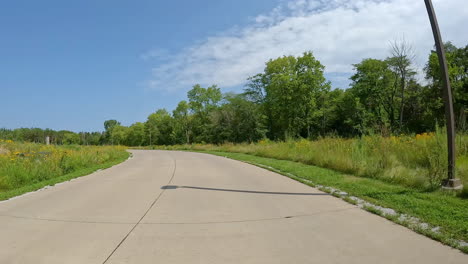 pov - driving on paved road thru jester county park in the des moines river vally in central iowa; driving past the park's nature center in late summer; vacation, holiday