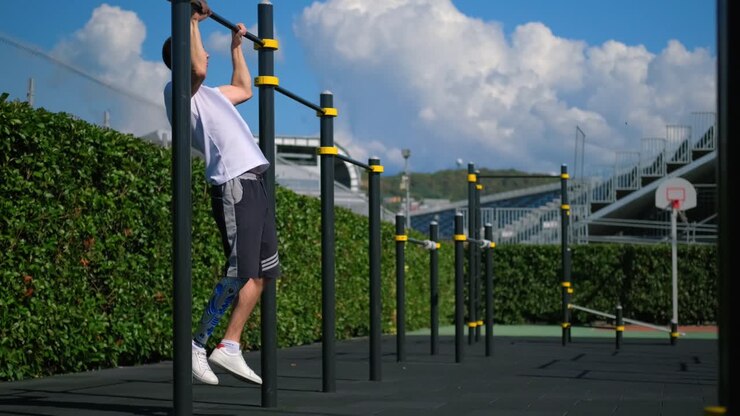 Man with prosthetic leg doing pull-ups at an outdoor workout area