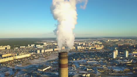 aerial orbital shot around a heavily polluting factory chimney, as white smoke arise in a post soviet country