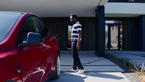 man charging electric car at home
