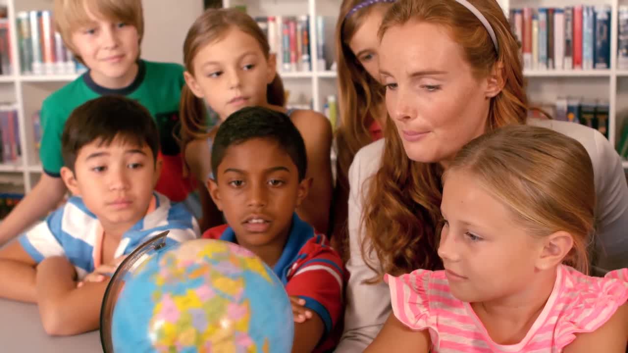 Lærer og skolebørn studerer globus på biblioteket