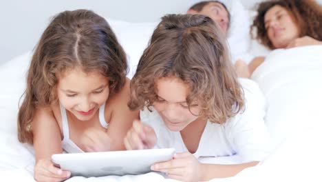 niños jugando con la tableta mientras los padres hablan