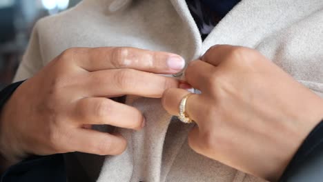 mujer abotonando un abrigo beige