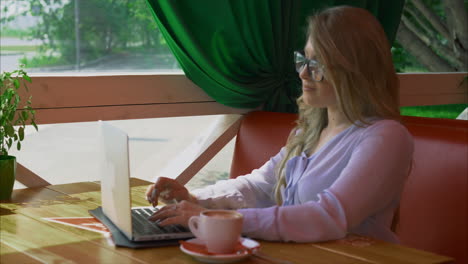 mujer trabajando en una computadora portátil en un café
