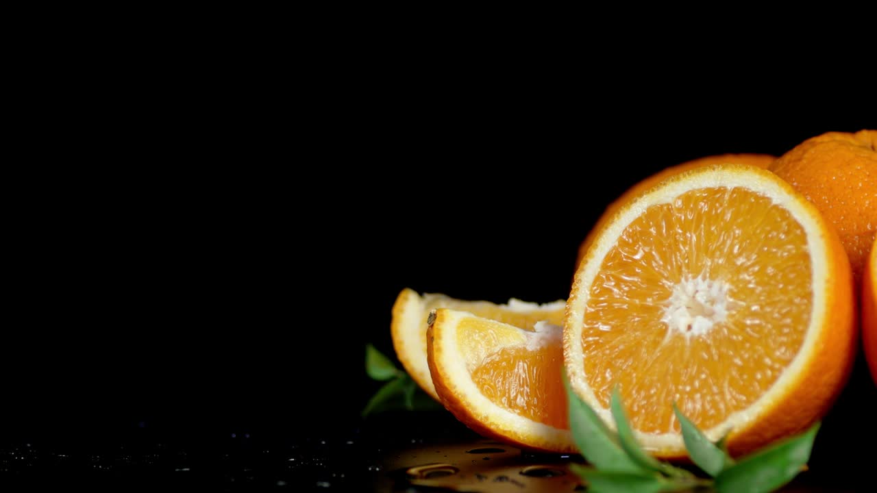 Slices of ripe orange with leaves slowly rotate.