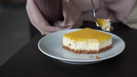 mujer comiendo una rebanada de pastel de queso de limón