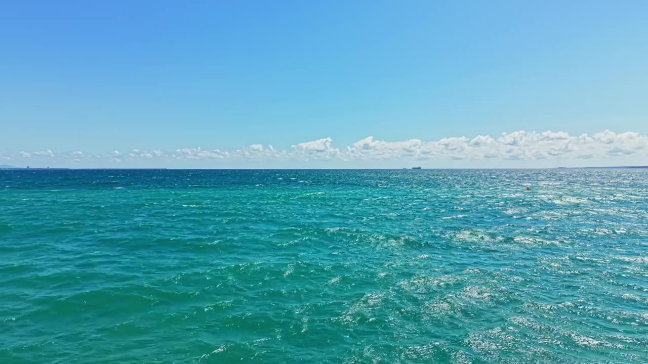 Ampia vista sull'oceano con onde e nuvole in una giornata di sole sulla spiaggia in estate.