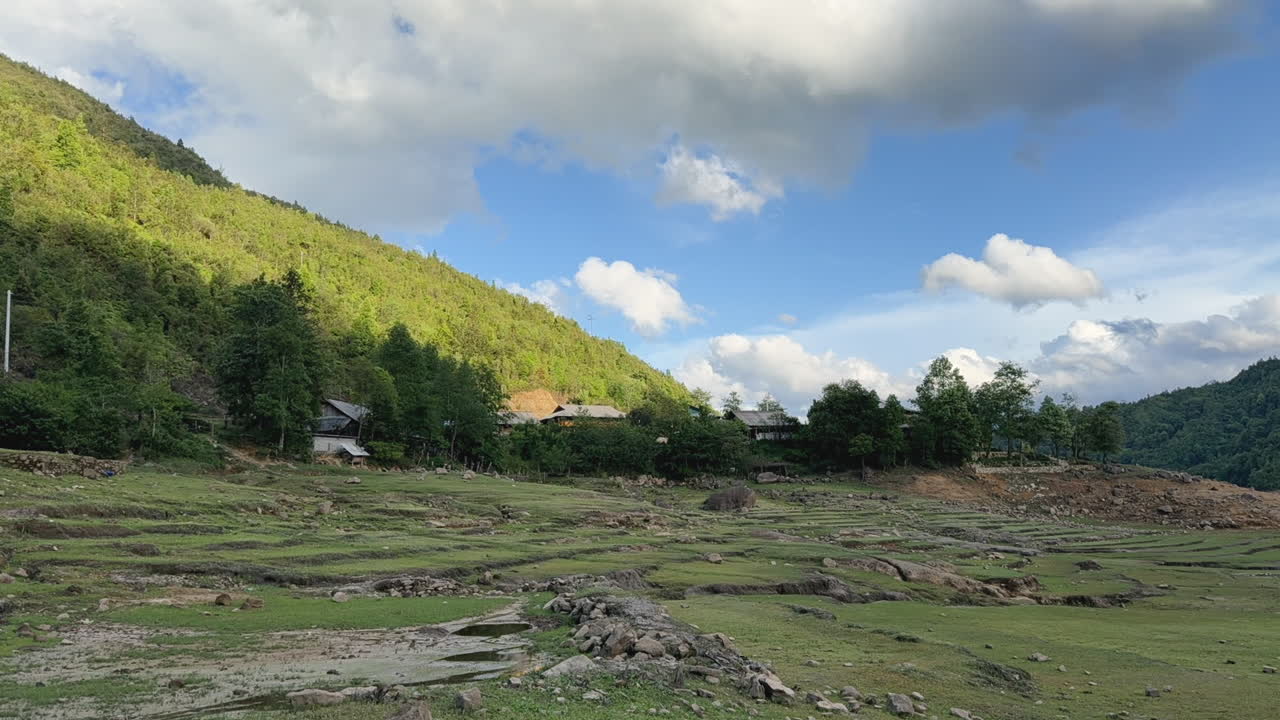 Cloud shadows moving swiftly across a forested mountain under a partly cloudy sky. Fixed camera captures shifting light and natural movement.