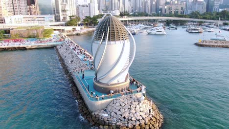 people walking on a breakwater with central wanchai bypass east vent shaft in causeway bay, hong kong