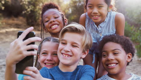 group of multi-cultural children posing for selfie with friends in countryside together