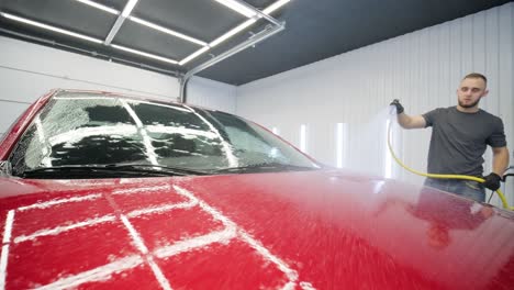 car washing cleaning with foam and high pressured water. red car