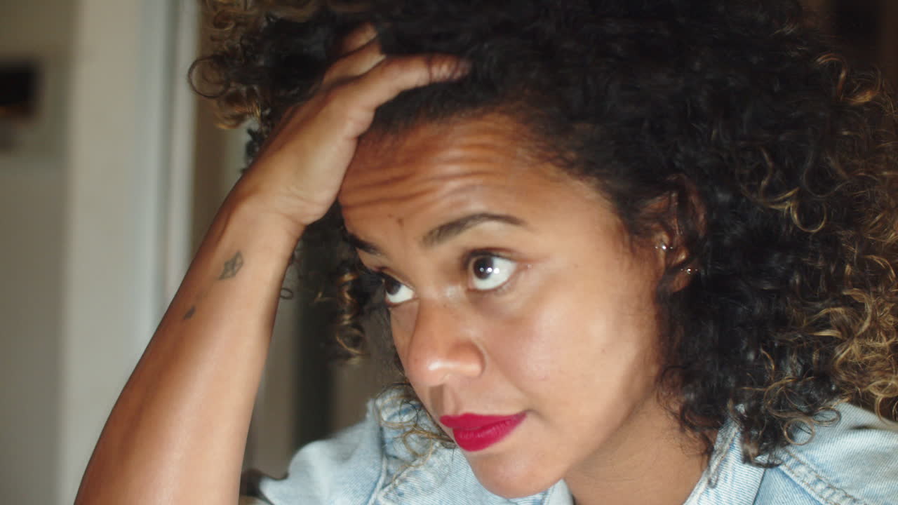 Serious American woman looking at mirror and fixing hair