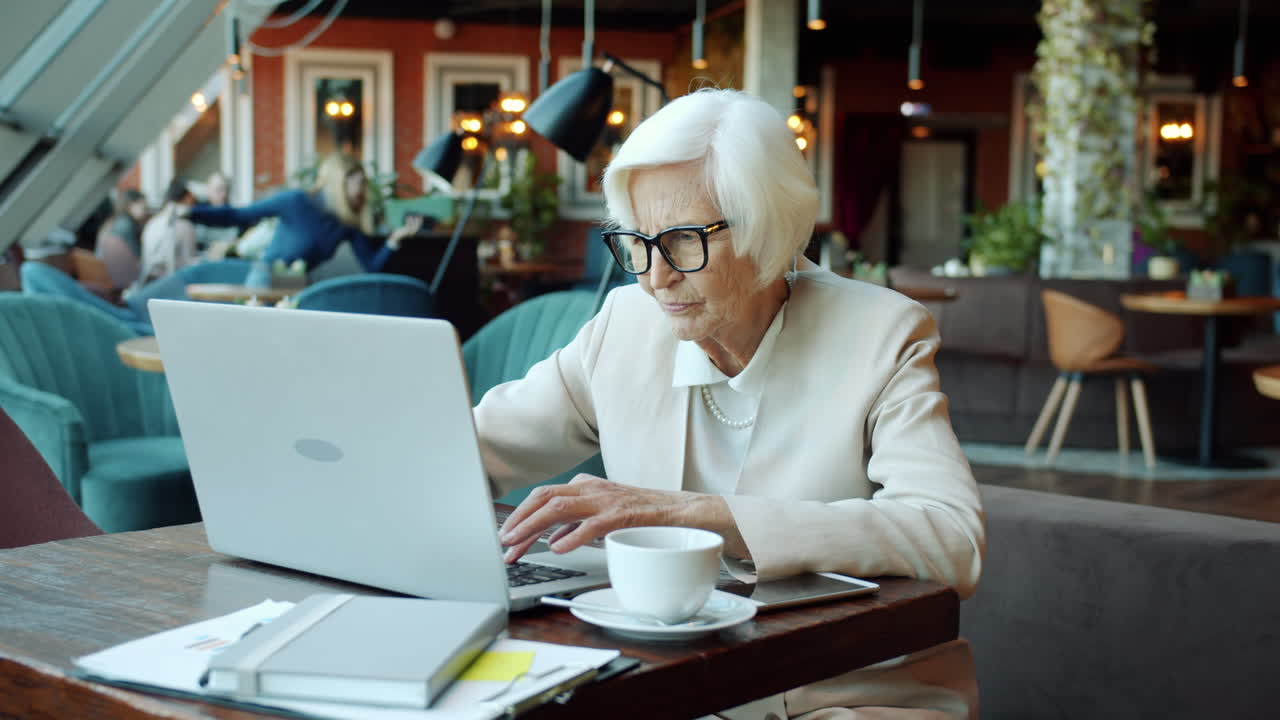 Senior Woman Working on Laptop in a Cafe