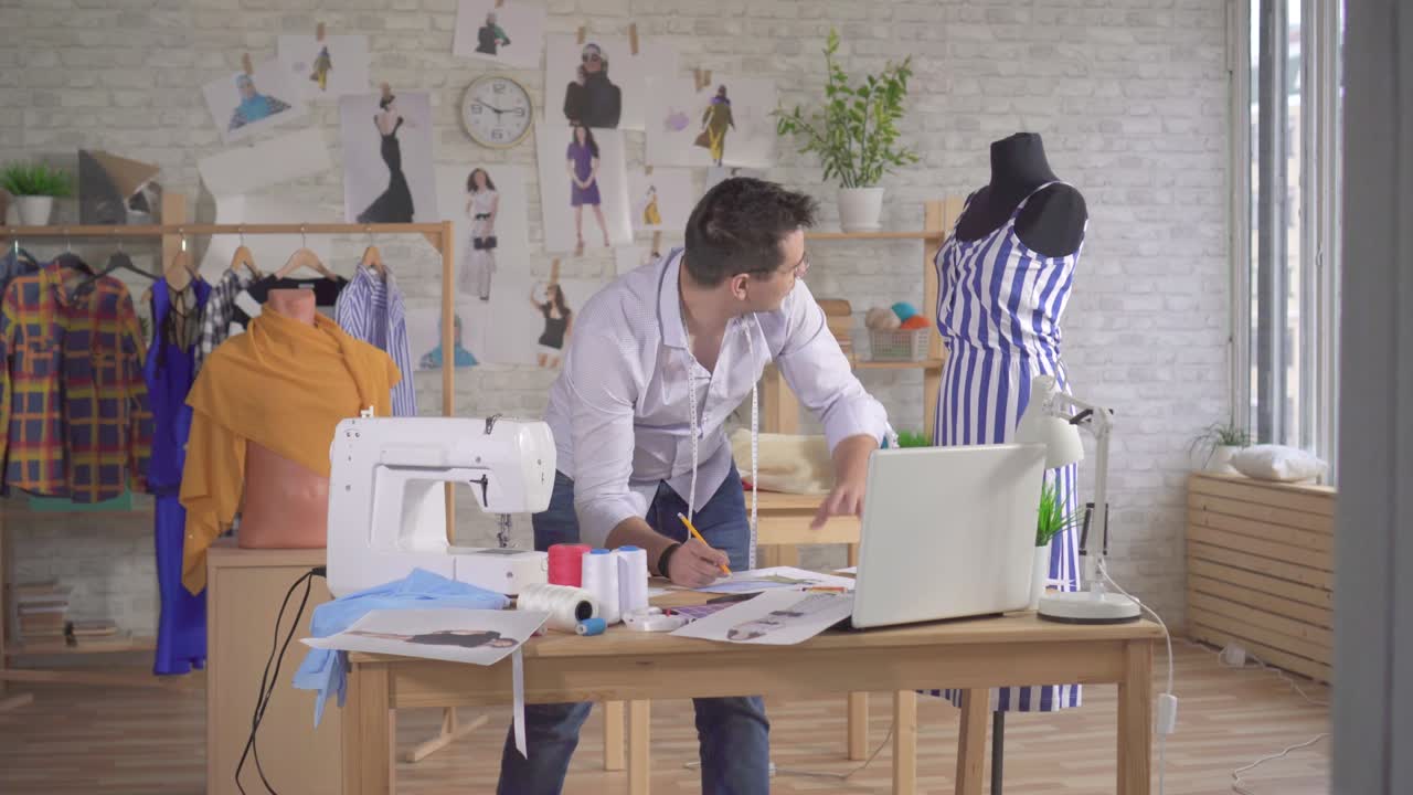 el diseñador de moda con una cinta de medir dibuja bocetos en un estudio moderno