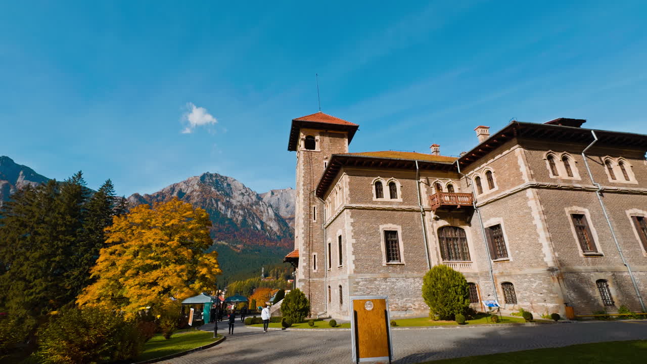 Beautiful old-fashioned historic building in the surrounding of autumn trees. Gorgeous mountains at backdrop.