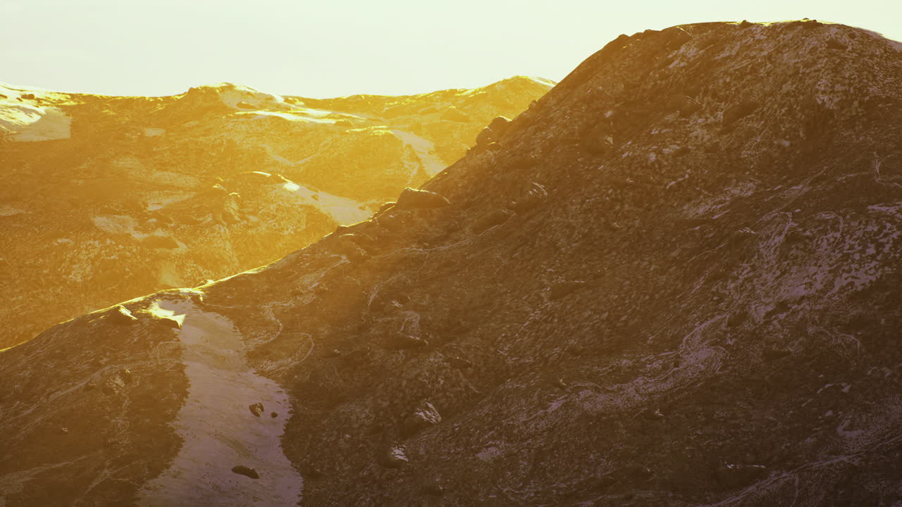 Golden sunlight bathes rugged mountain terrain at sunset