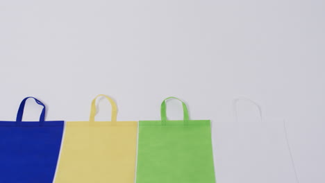 video of row of multi coloured canvas bags with copy space on white background