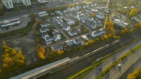 Toma-Aérea-De-Arriba-Hacia-Abajo-Del-Tren-Público-Que-Pasa-Por-El-Distrito-De-La-Zona-De-Viviendas-En-Gdynia-Durante-El-Amanecer