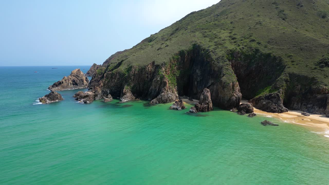 Drone view over green cliffs next to tropical ocean