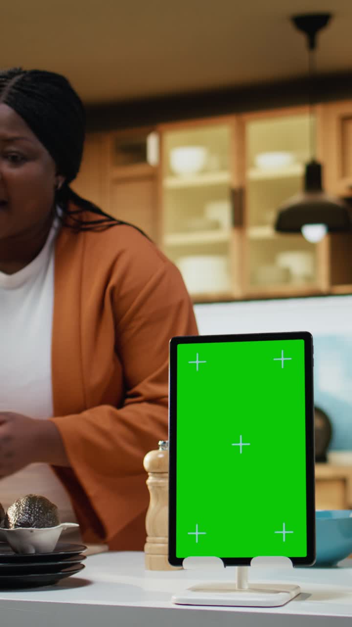 Video verticale, tablet verticale, schermo verde, influencer afroamericano che filma un vlog culinario.