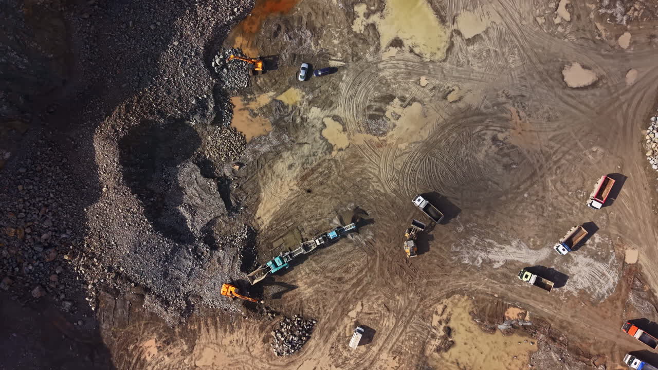 Granite quarry operation in an industrial site with machinery and transport vehicles engaged in the stone extraction process