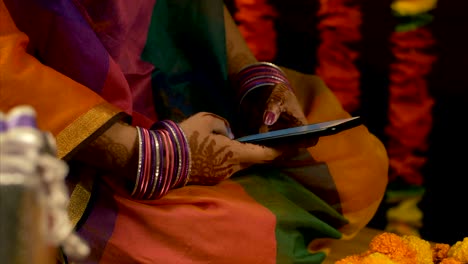 woman with mehandi / henna tattoo on her hand texting on a smartphone