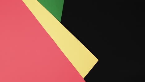 Video-of-red,-yellow-and-green-papers-with-copy-space-on-black-background