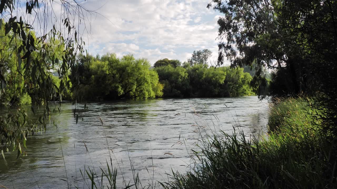 Wide view of the Tumut River with overhanging trees flowing strongly in the Snowy Mountain Region of Australia, New South Wales.