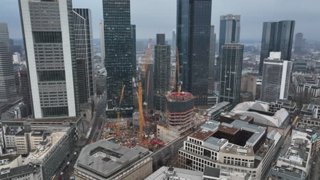 Modern-tall-skyscrapers-in-business-district.-Tilt-down-focus-on-construction-site-with-machinery.-Frankfurt-am-Main,-Germany