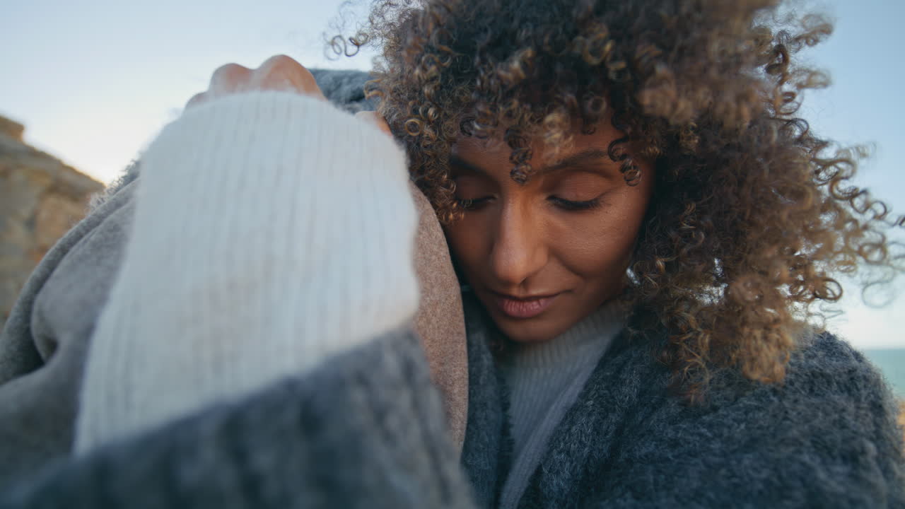 Curly girl bonding boyfriend at evening ocean coast closeup. Lovers cuddling