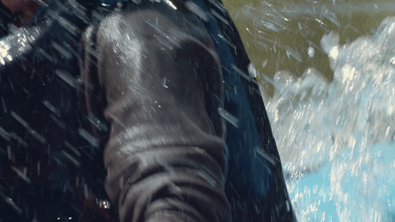 Woman paddles kayak in rapids as whitewater sprays, close-up