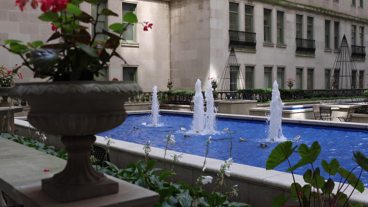 Exuberantes plantas de flores rojas complementan el ambiente sereno de apartamentos de lujo adornados con fuentes de agua, creando un oasis de elegancia