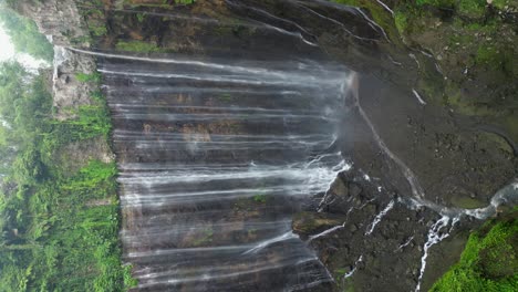 vertical format: lush jungle canyon waterfall in java, tumpak sewu