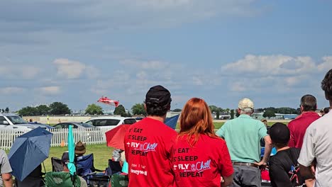 airshow: crowd watching red airplane stunt performance