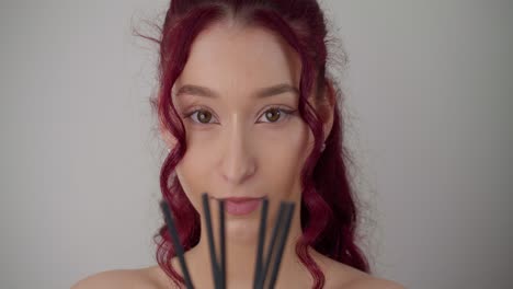 Pretty-young-indie-hipster-girl-with-pink-purple-hair-holding-incense-in-studio,-looking-into-camera