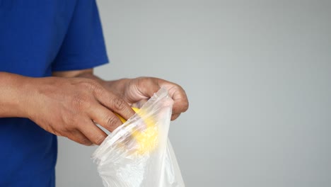 person putting a lemon in a plastic bag