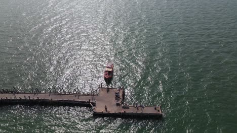 imágenes aéreas deslizándose hacia la derecha que revelan el muelle de pesca de pattaya con un barco de pesca y luego algunos vehículos en el muelle, pattaya, tailandia