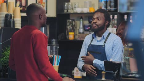 black man stands behind bar counter and talks