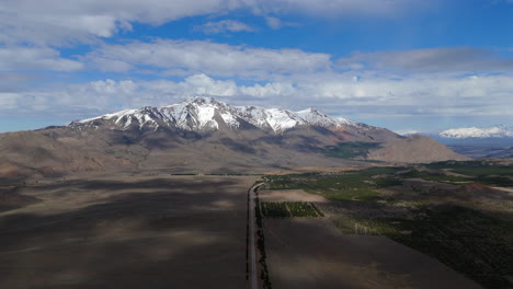 aerial drone footage of route 40, a remote and iconic highway surrounded by vast open fields and the majestic snow-capped andes mountains