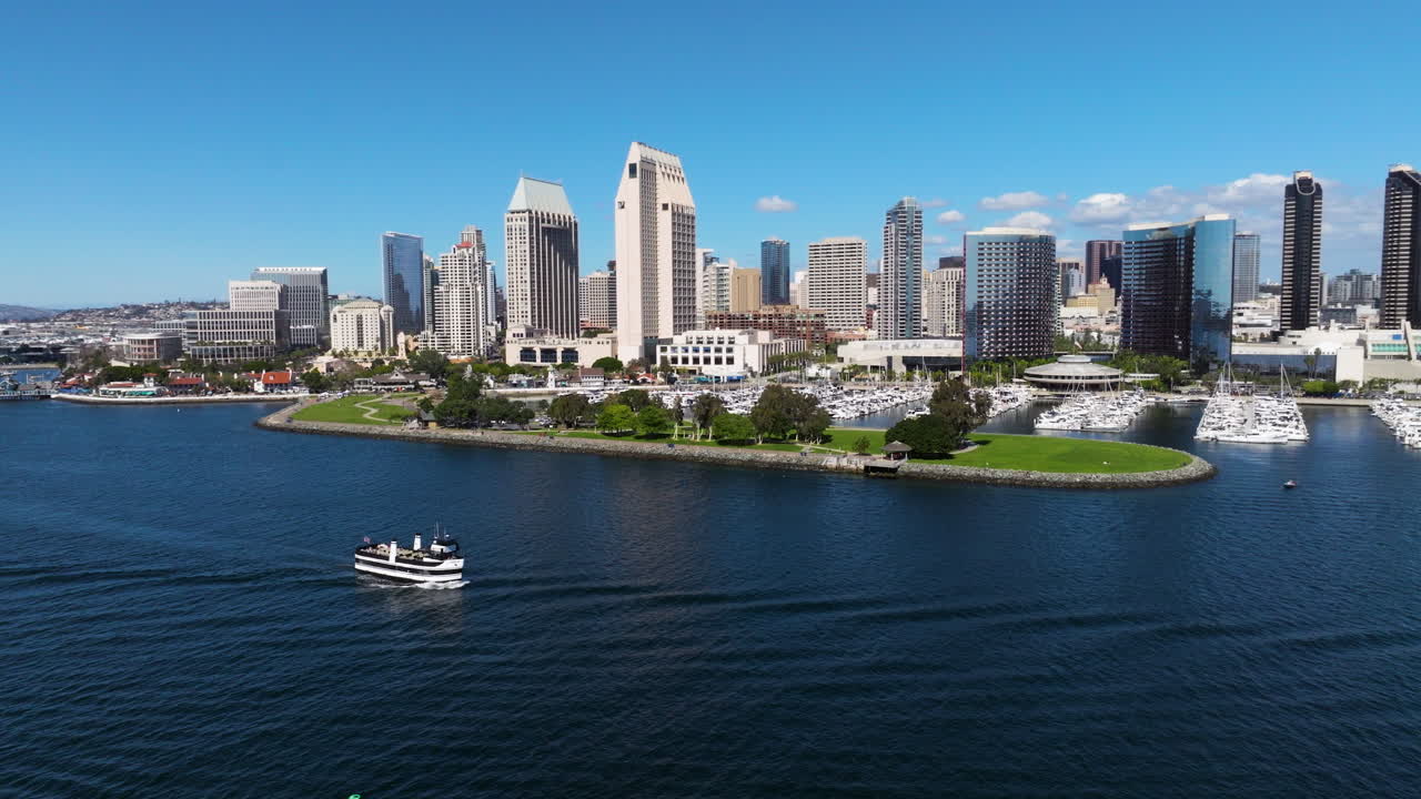 San Diego Skyline From The San Diego Bay With Boat Navigating In The Calm Water In California, USA. - aerial shot